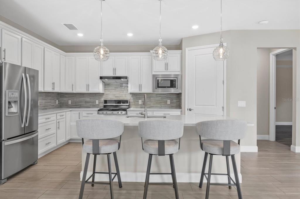 6835 Chester Trail Bradenton, FL 34202 - Photo 15 of 40 a kitchen with stainless steel appliances granite countertop a stove a refrigerator a kitchen island and chairs with wooden floor