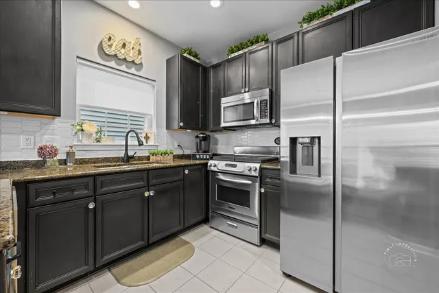 a kitchen with kitchen island granite countertop a sink stainless steel appliances and cabinets