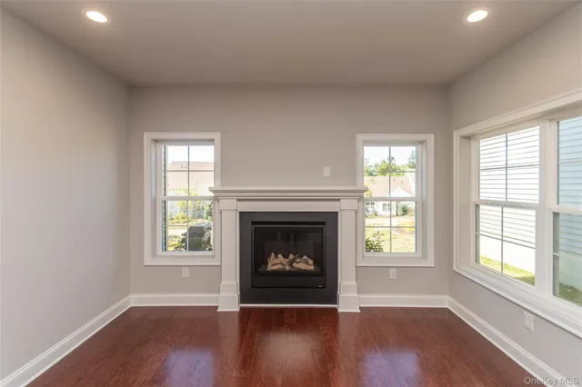 an empty room with wooden floor fireplace and windows