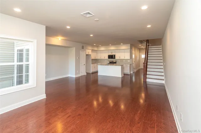 a view of a big room with wooden floor and windows