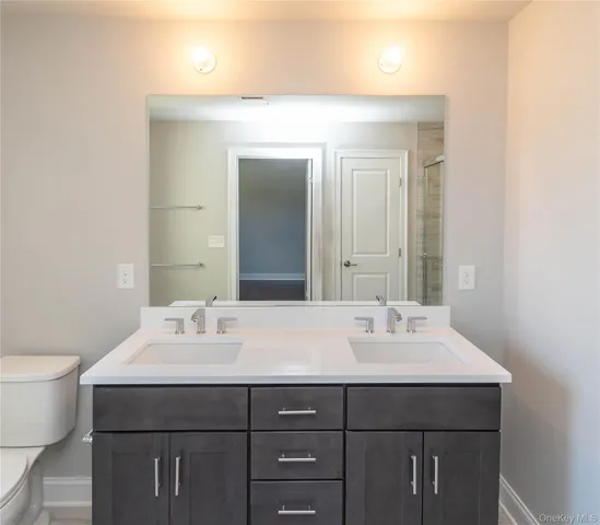 a bathroom with double vanity sink a mirror and a toilet