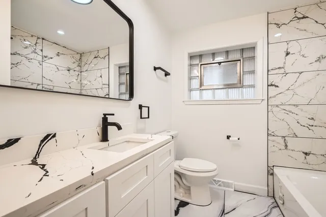 a bathroom with a granite countertop sink toilet and a mirror