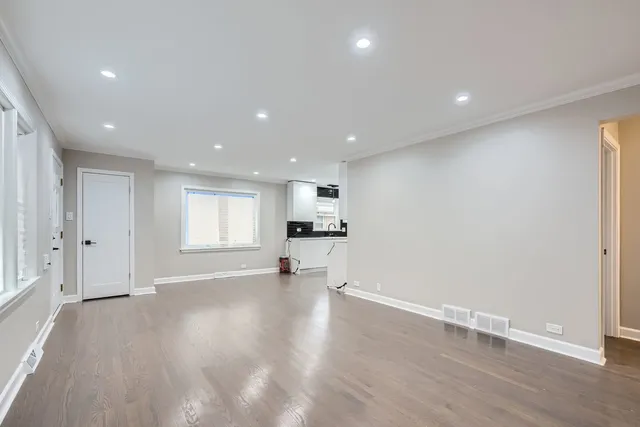 a view of an empty room with a window and wooden floor