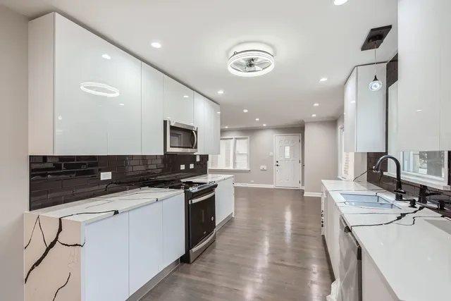 a view of a kitchen with kitchen island a sink stainless steel appliances and cabinets