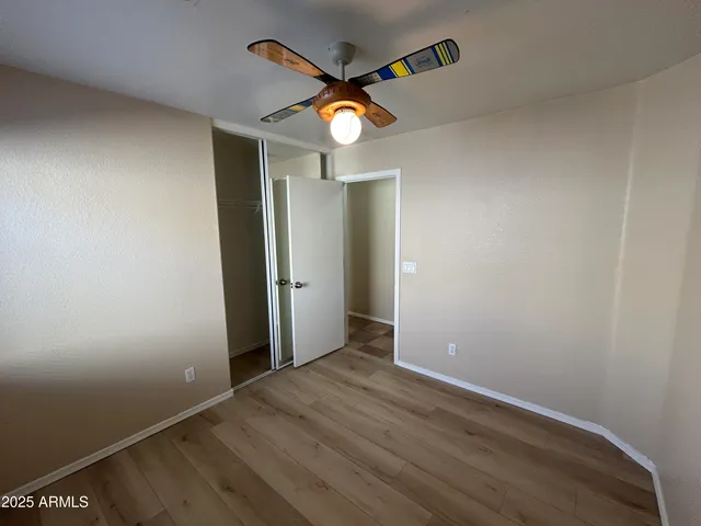 an empty room with wooden floor and a ceiling fan
