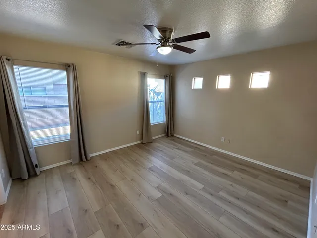 an empty room with wooden floor and a ceiling fan