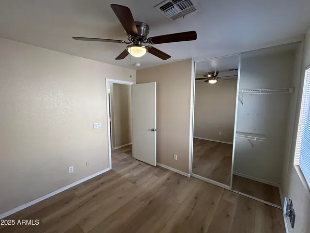 an empty room with wooden floor fan and windows
