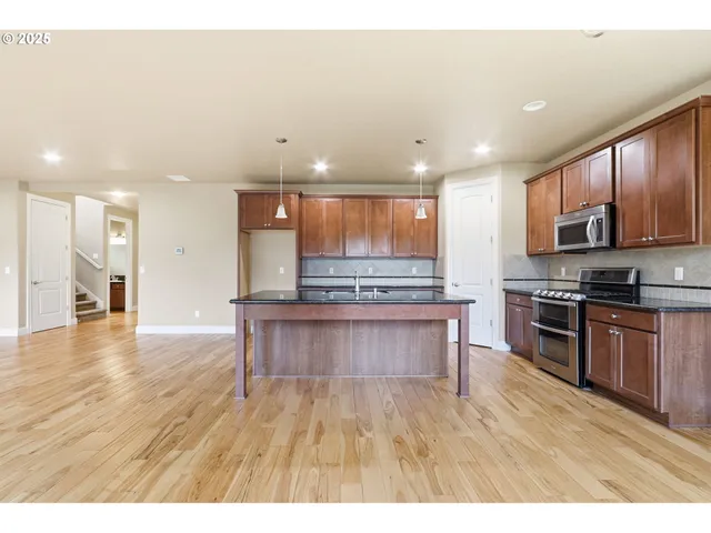 a open kitchen with stainless steel appliances granite countertop a stove a sink a refrigerator and a microwave