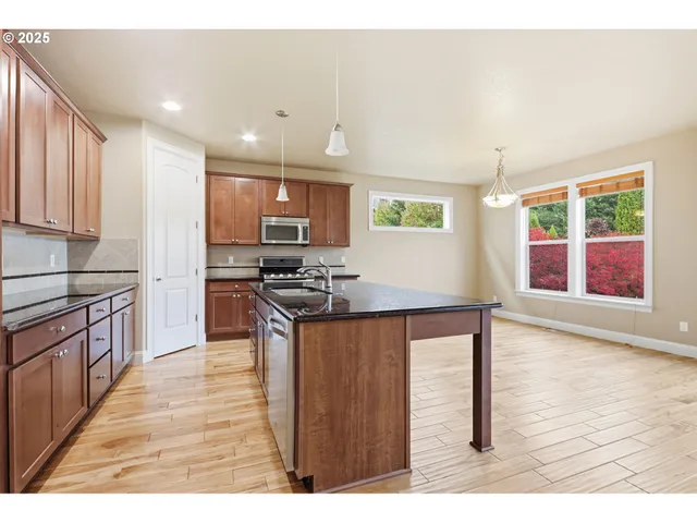 a kitchen with stainless steel appliances granite countertop a stove top oven a sink a counter space and cabinets