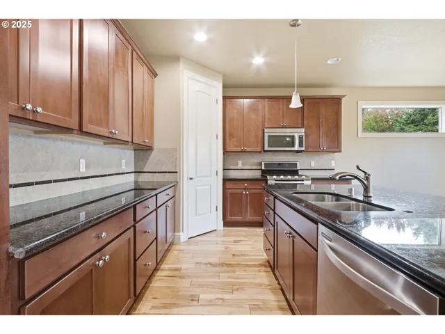 a kitchen with stainless steel appliances granite countertop a stove a sink and a microwave