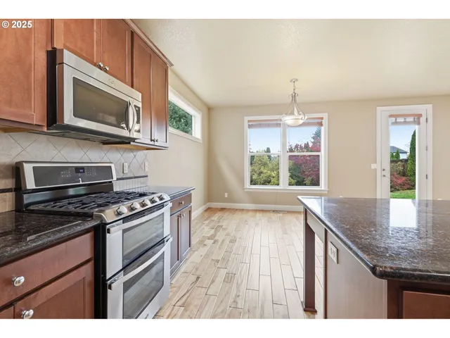 a kitchen with stainless steel appliances granite countertop a stove microwave and sink