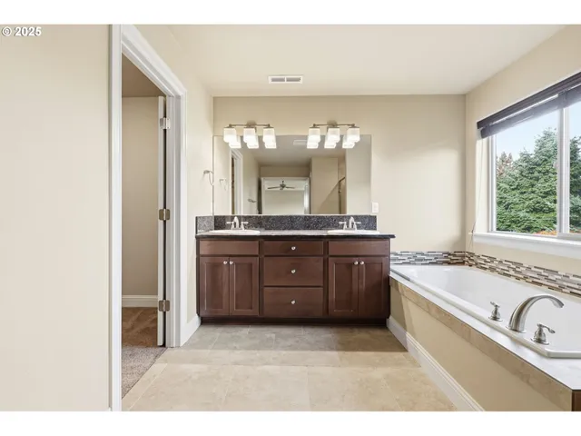 a bathroom with a granite countertop sink a large mirror and a bathtub