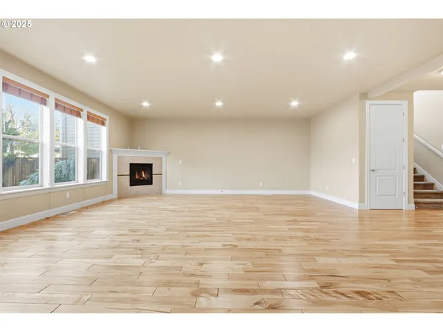 a view of empty room with wooden floor and fireplace