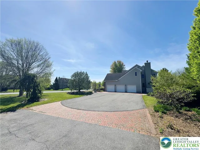 a view of a house with a yard and large trees
