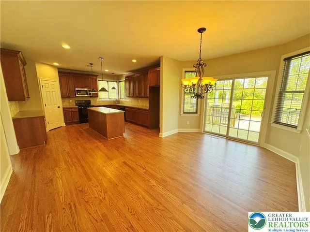 a open kitchen with stainless steel appliances granite countertop a dishwasher kitchen island a stove and a wooden floors