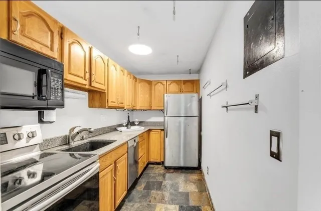 a kitchen with stainless steel appliances a sink a stove a refrigerator cabinets and a window