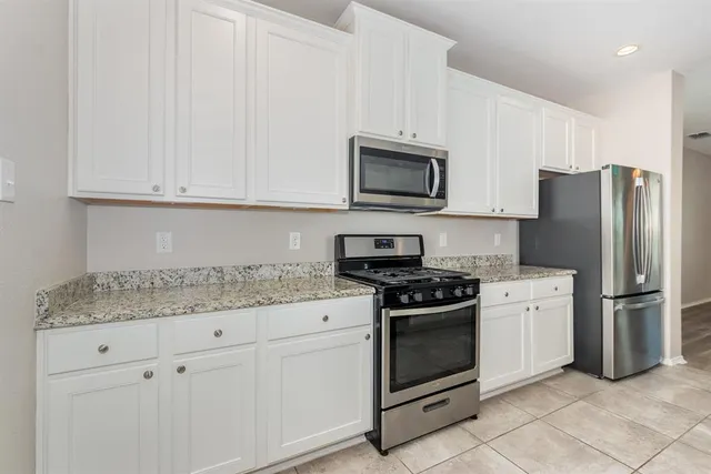 a kitchen with white cabinets and stainless steel appliances