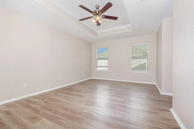 a view of an empty room with window and wooden floor
