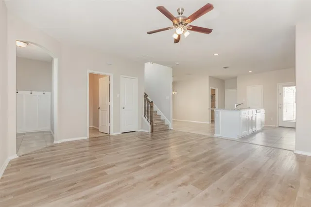 a view of an empty room with wooden floor and a ceiling fan