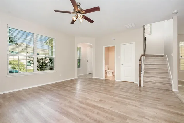 a view of empty room with wooden floor and fan