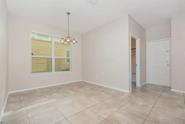 a view of an empty room with window and chandelier fan