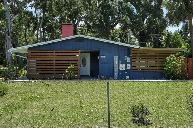 a backyard of a house with wooden fence and large trees