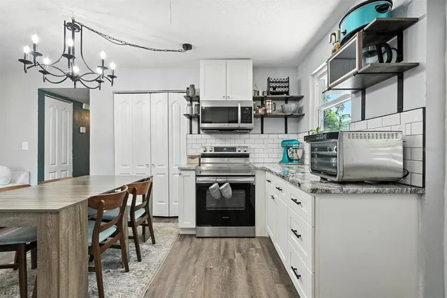 a kitchen with stainless steel appliances granite countertop a stove top oven a sink dishwasher and a refrigerator with wooden floor