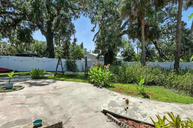 a view of a backyard with potted plants and large trees