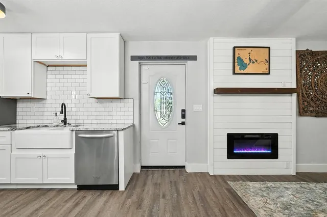 a kitchen with stainless steel appliances granite countertop a stove top oven a sink and a refrigerator with wooden floors