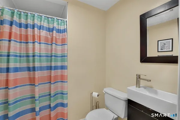 a bathroom with a sink a toilet a mirror and shower curtain