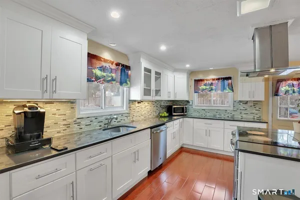 a kitchen with granite countertop a sink stainless steel appliances and cabinets