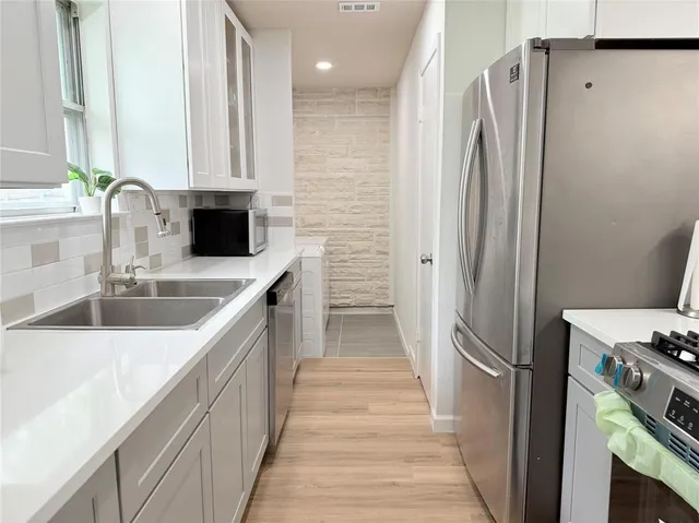 a kitchen with stainless steel appliances a refrigerator sink and white cabinets