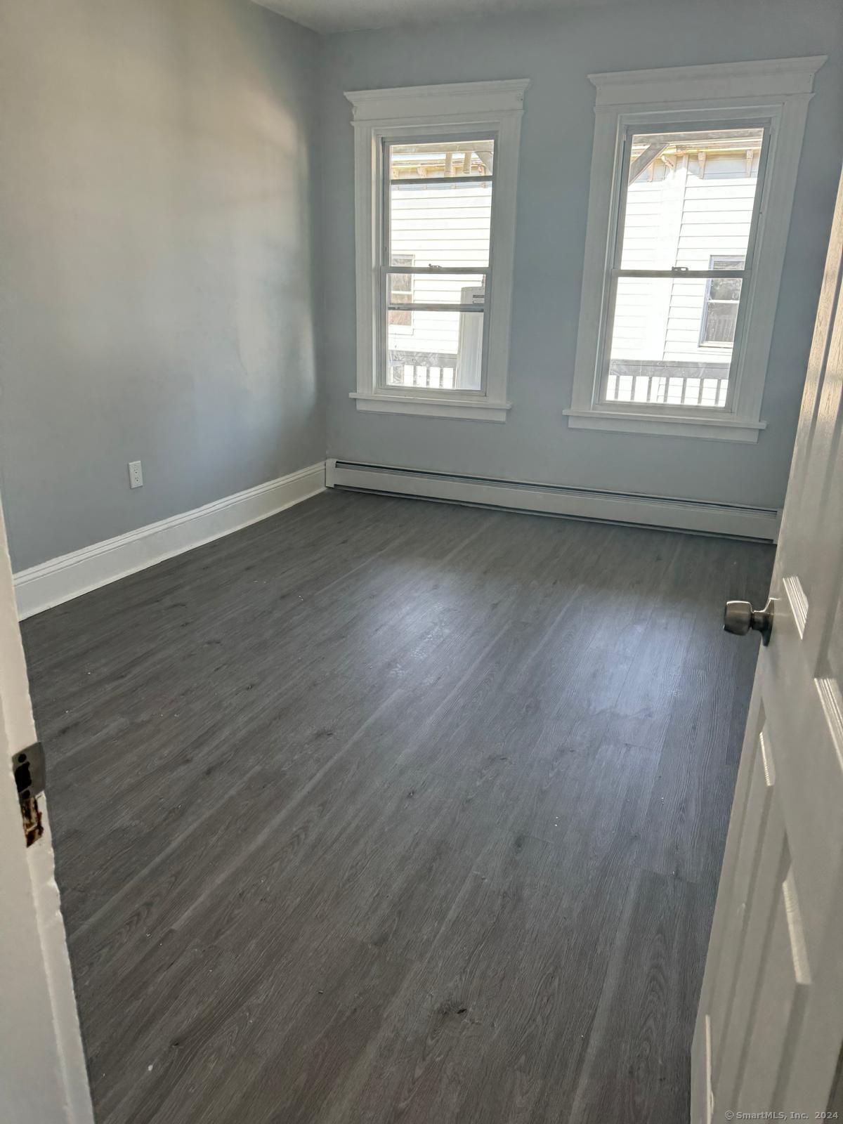 2336 Barnum Avenue, Unit FRONT E Stratford, CT 06615 - Photo 11 of 12 an empty room with wooden floor and windows