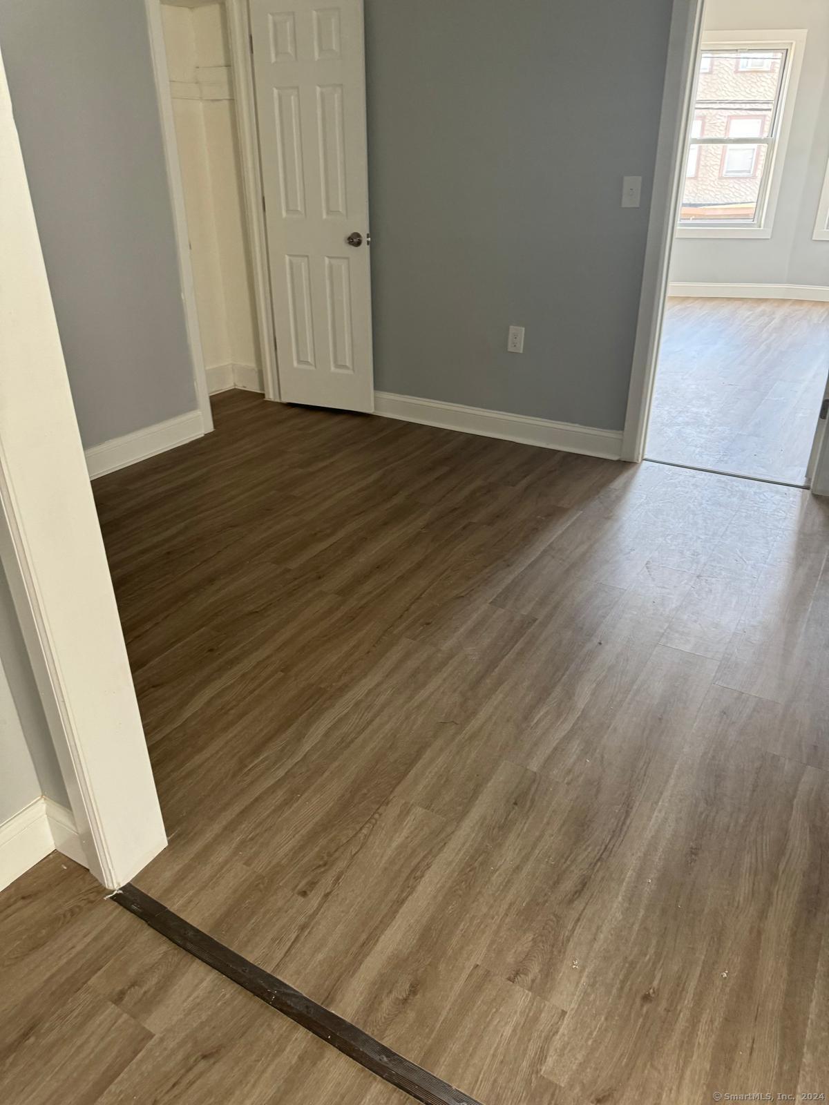2336 Barnum Avenue, Unit FRONT E Stratford, CT 06615 - Photo 3 of 12 a view of an empty room with wooden floor and a window