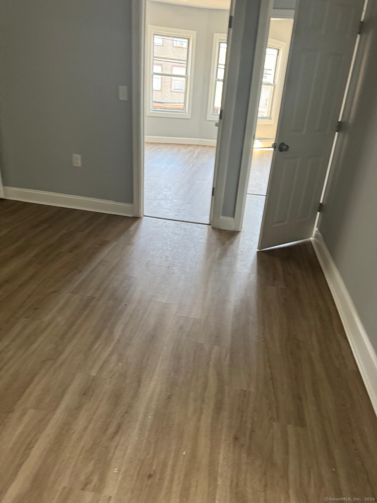 2336 Barnum Avenue, Unit FRONT E Stratford, CT 06615 - Photo 4 of 12 an empty room with wooden floor and windows