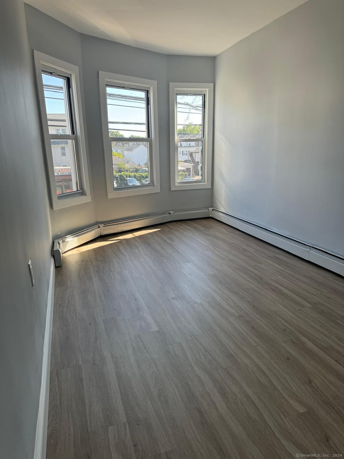 2336 Barnum Avenue, Unit FRONT E Stratford, CT 06615 - Photo 5 of 12 a view of an empty room with wooden floor and a window