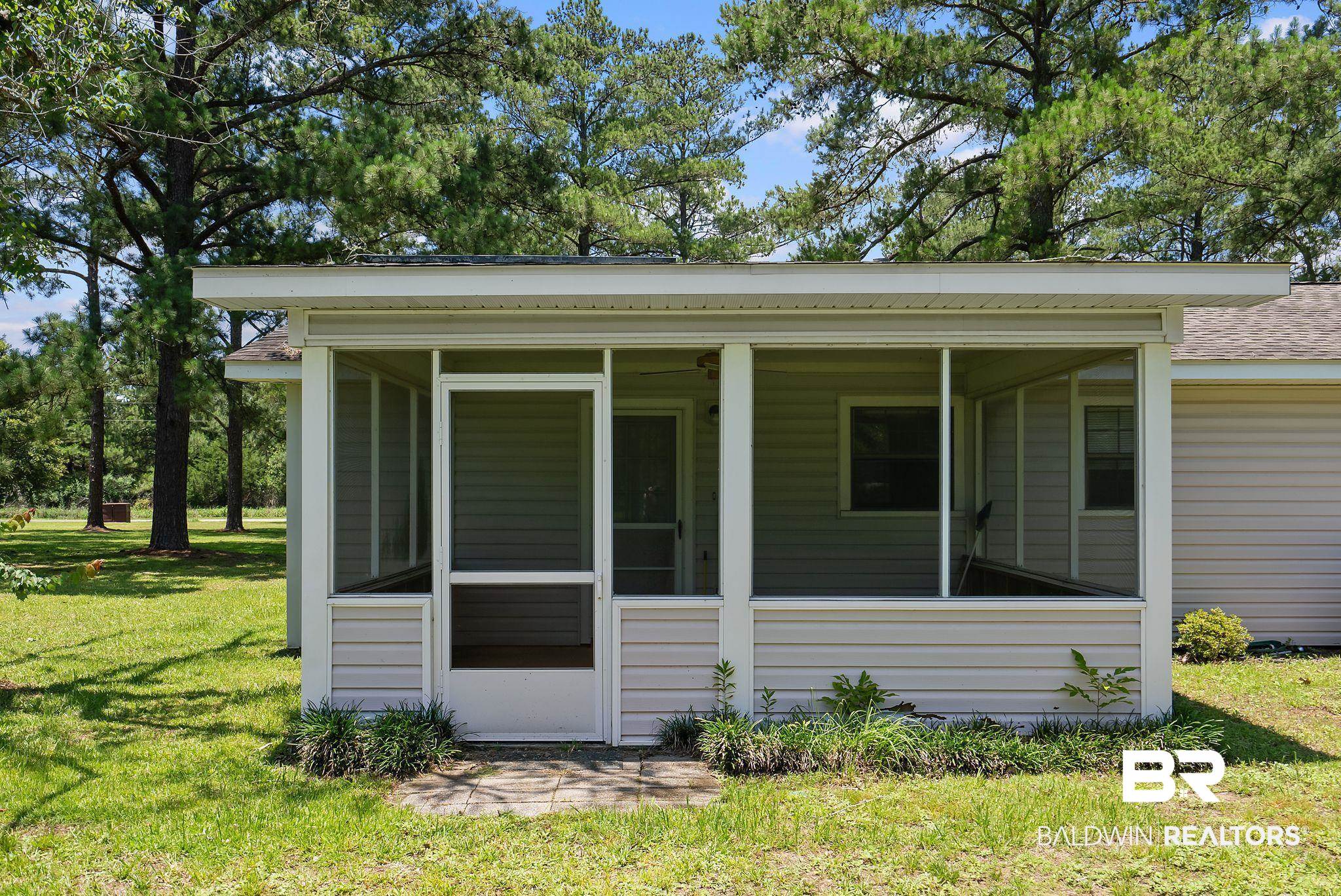 20540 Lacey Road Silverhill, AL 36576 - Photo 25 of 40 Screened porch featuring light-toned vinyl siding, an access door, and a shingled roofline