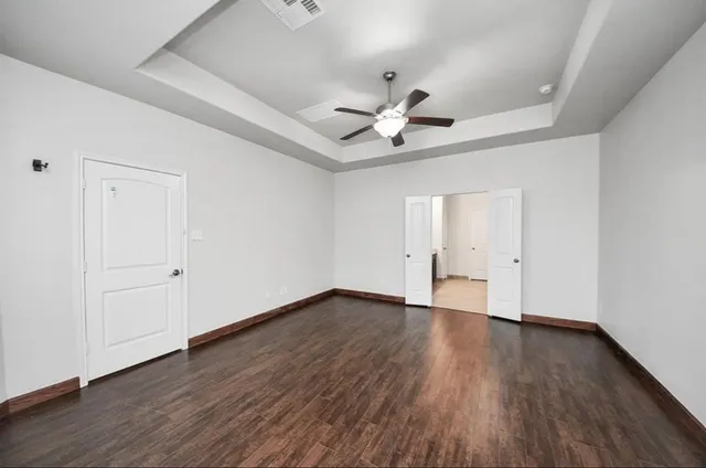 an empty room with wooden floor and windows