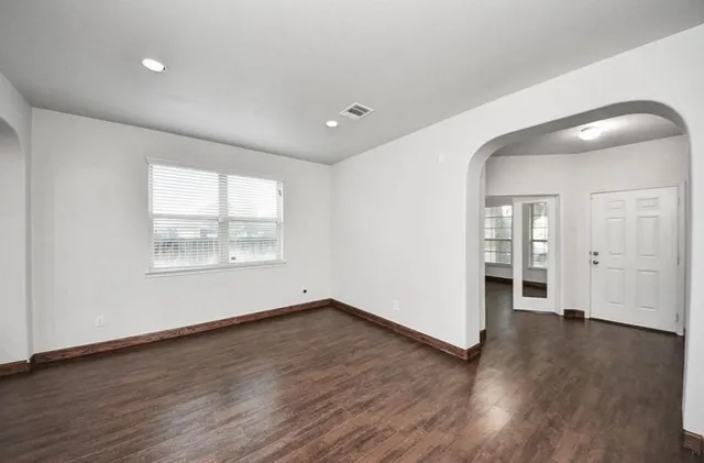 an empty room with wooden floor and windows