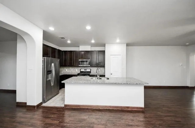a large kitchen with kitchen island granite countertop a large counter top stainless steel appliances and cabinets