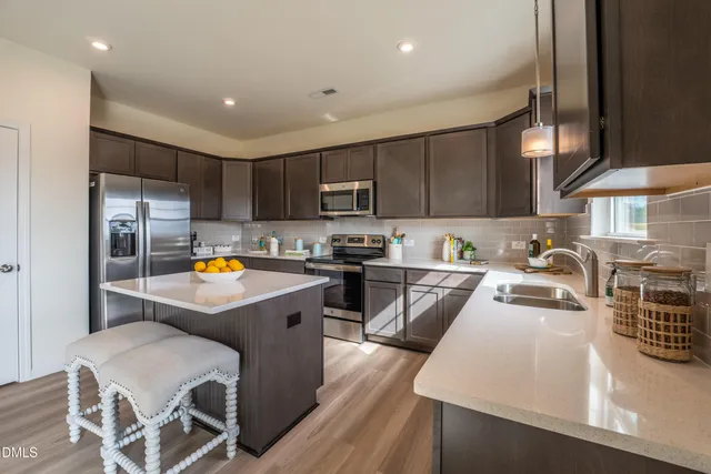 a kitchen with granite countertop a stove top oven a sink dishwasher a dining table and chairs with wooden floor