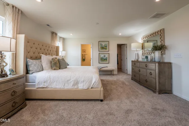 a spacious bedroom with a bed a window and dresser