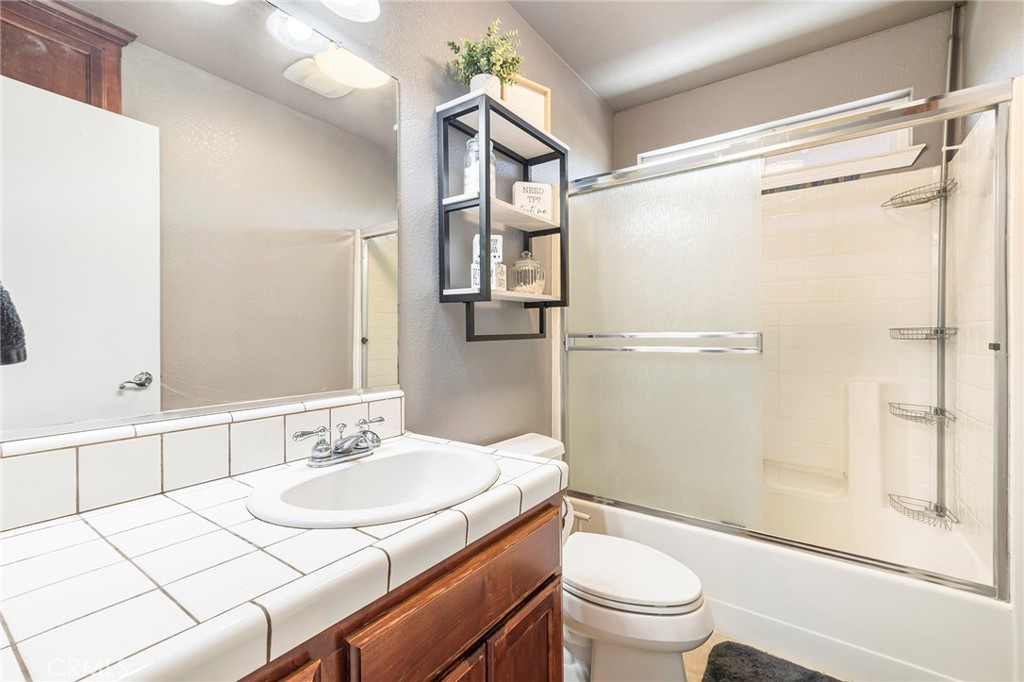 23446 Capay Road Corning, CA 96021 - Photo 28 of 64 a bathroom with a granite countertop sink toilet a mirror and shower