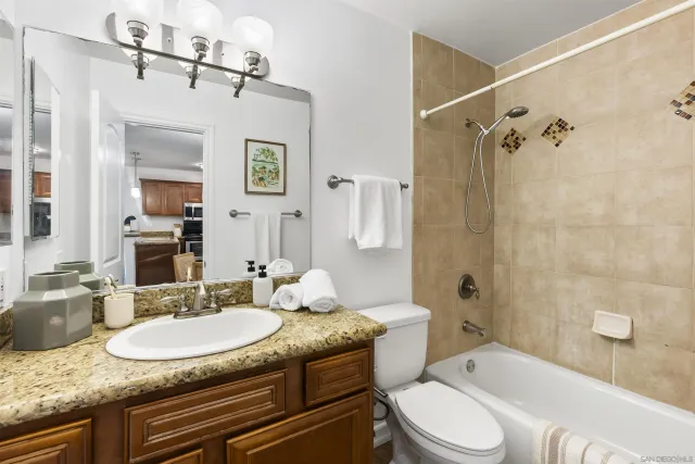 a bathroom with a granite countertop sink toilet a mirror and shower