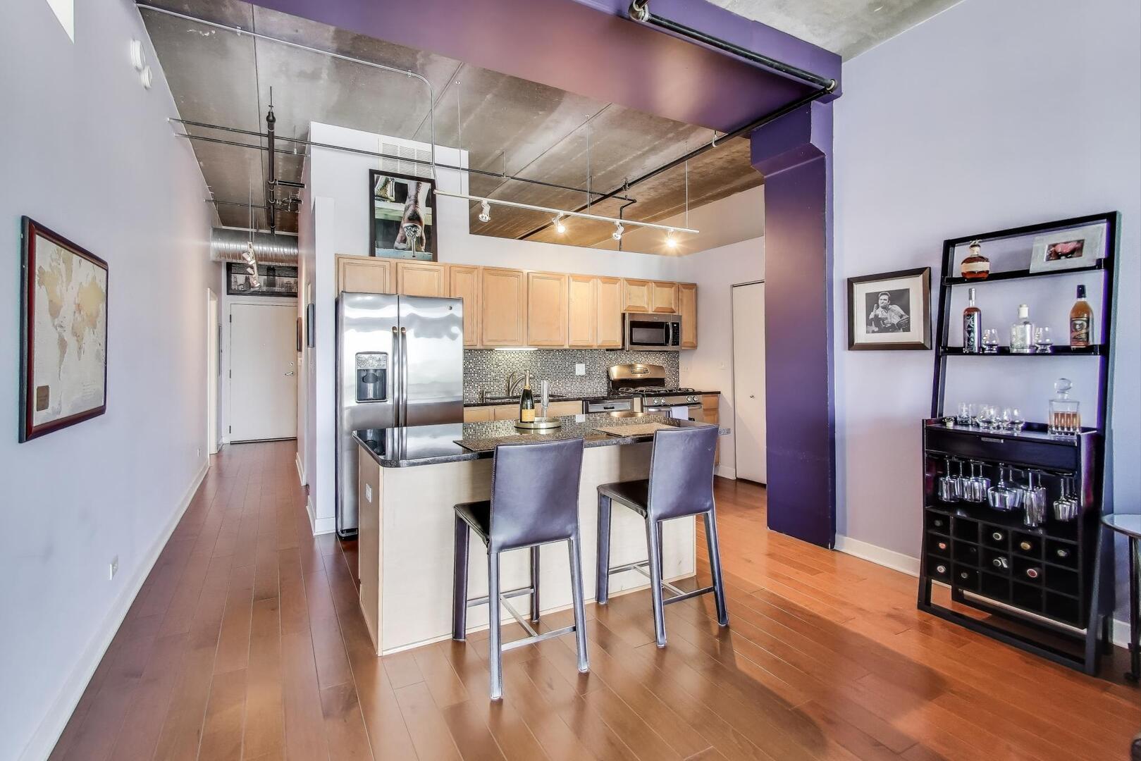833 West 15th Place, Unit 606W Chicago, IL 60608 - Photo 11 of 47 a kitchen with stainless steel appliances kitchen island granite countertop a refrigerator a stove and white cabinets with wooden floor