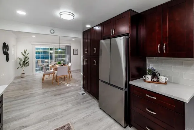 a kitchen with a refrigerator a stove and a dining table with wooden floor
