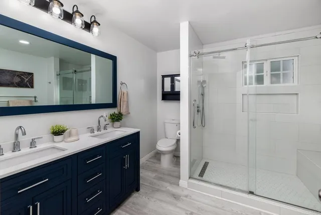 a spacious bathroom with a double vanity sink toilet mirror and shower