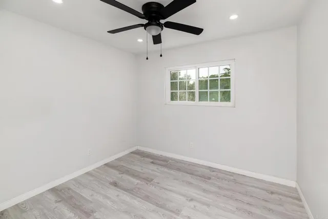 an empty room with a window and a fan