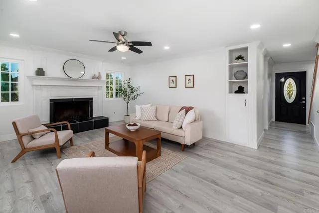 a living room with furniture a fireplace and a ceiling fan