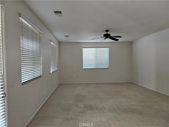 an empty room with windows and ceiling fan